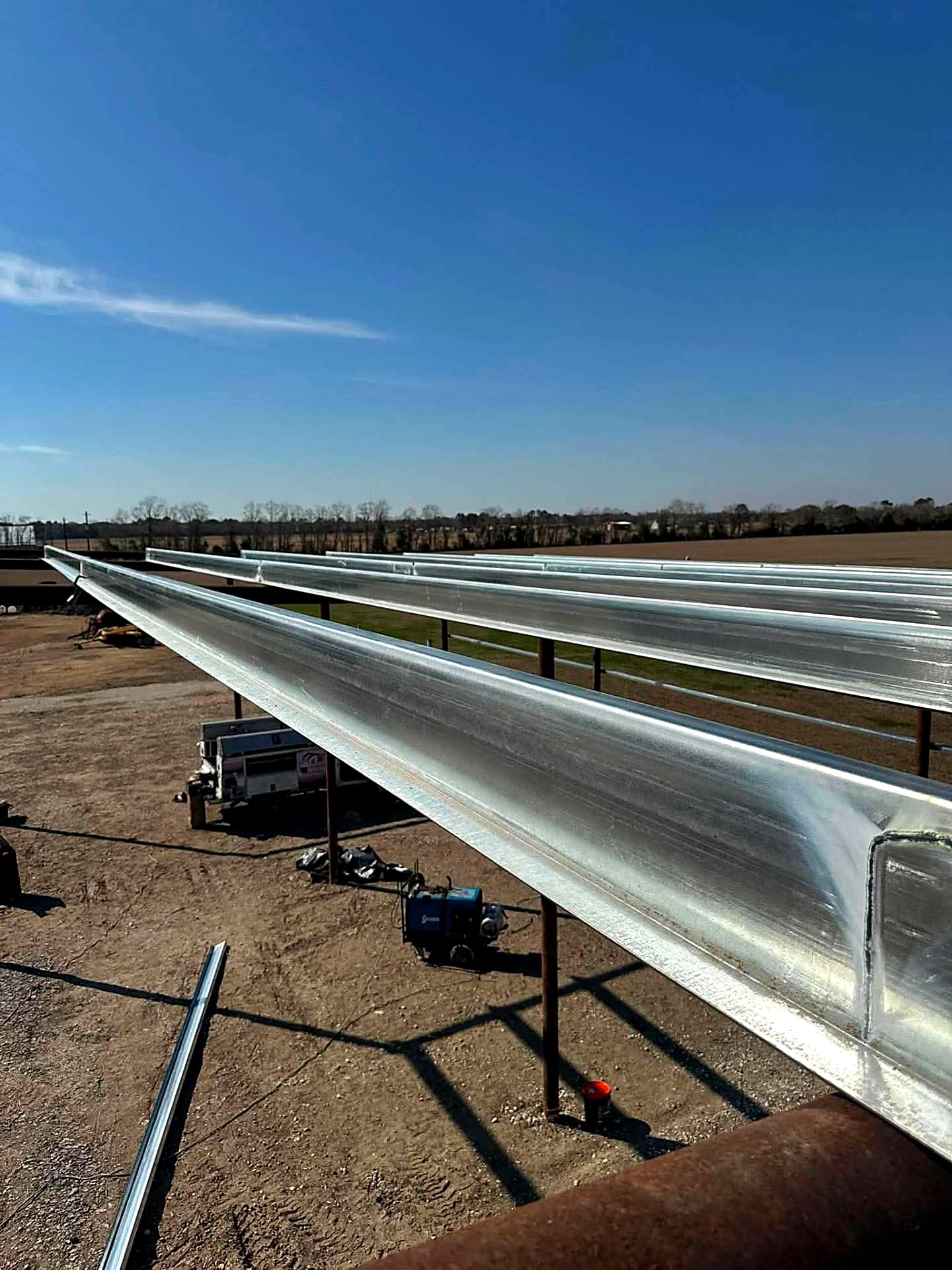 Long galvanized steel beams set across posts on a new structure