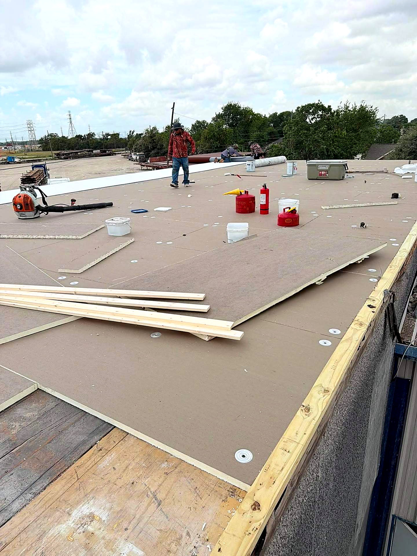 ISO board laid and fastened across a flat roof deck with crew working