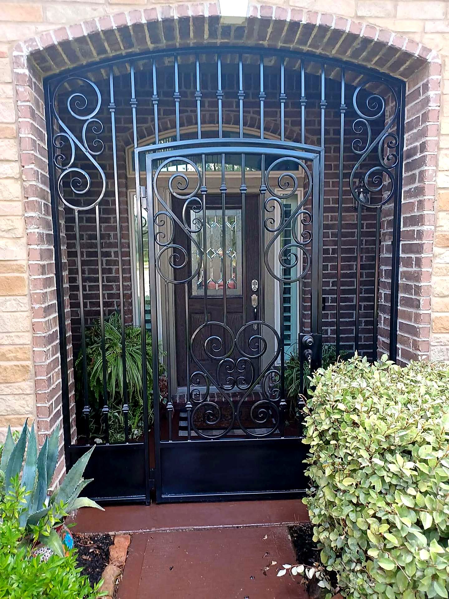 Custom wrought iron entry enclosure with scrollwork on a brick Houston home