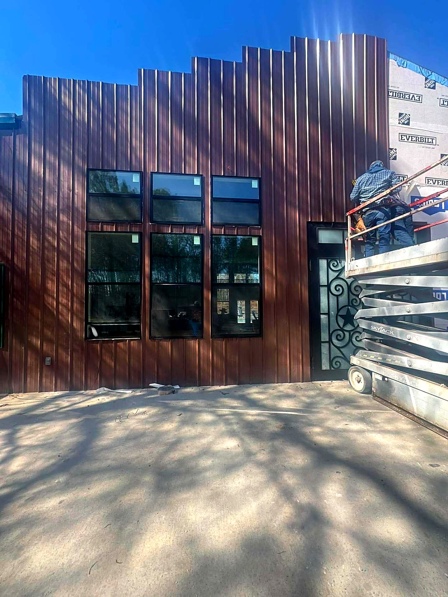 Completed brown metal siding with black-framed windows on a Texas building