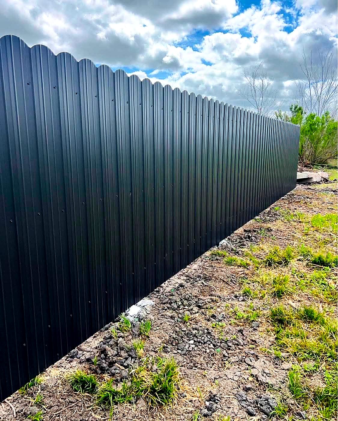Black corrugated metal fence with a scalloped top edge