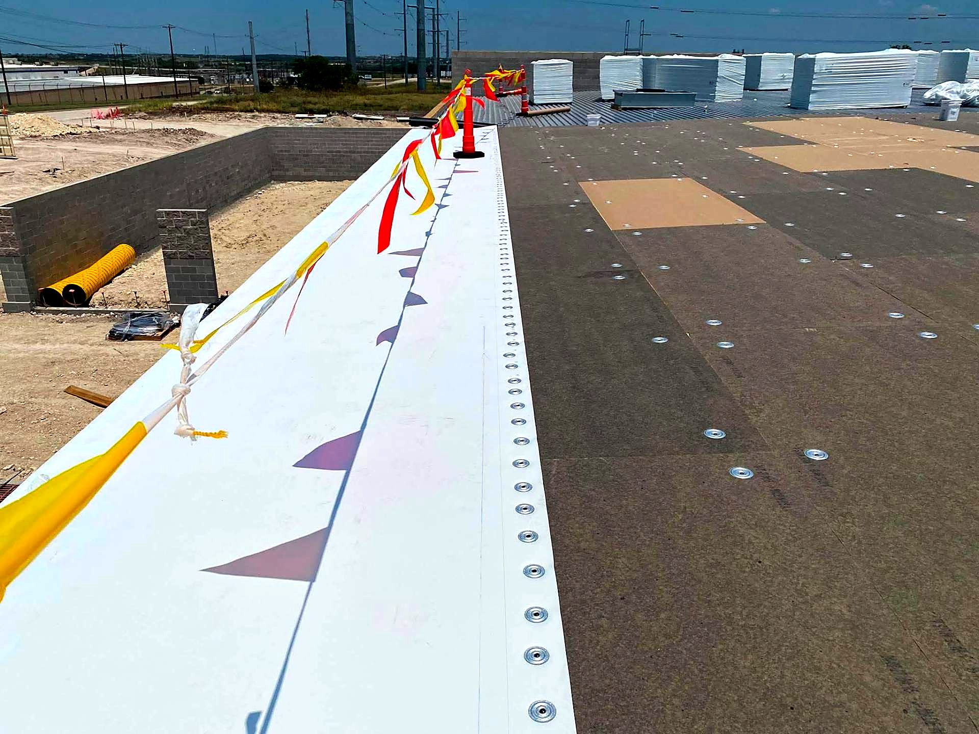Membrane edge run with fastener plates along a parapet wall