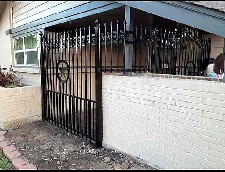 Black iron fence with star panels set on a painted brick wall