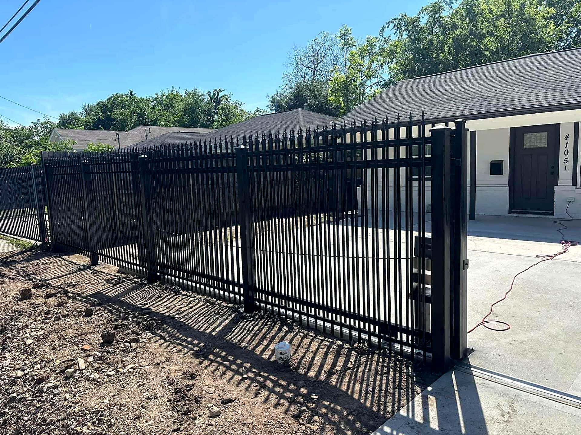 Spear-top iron fence and rolling gate across a residential driveway