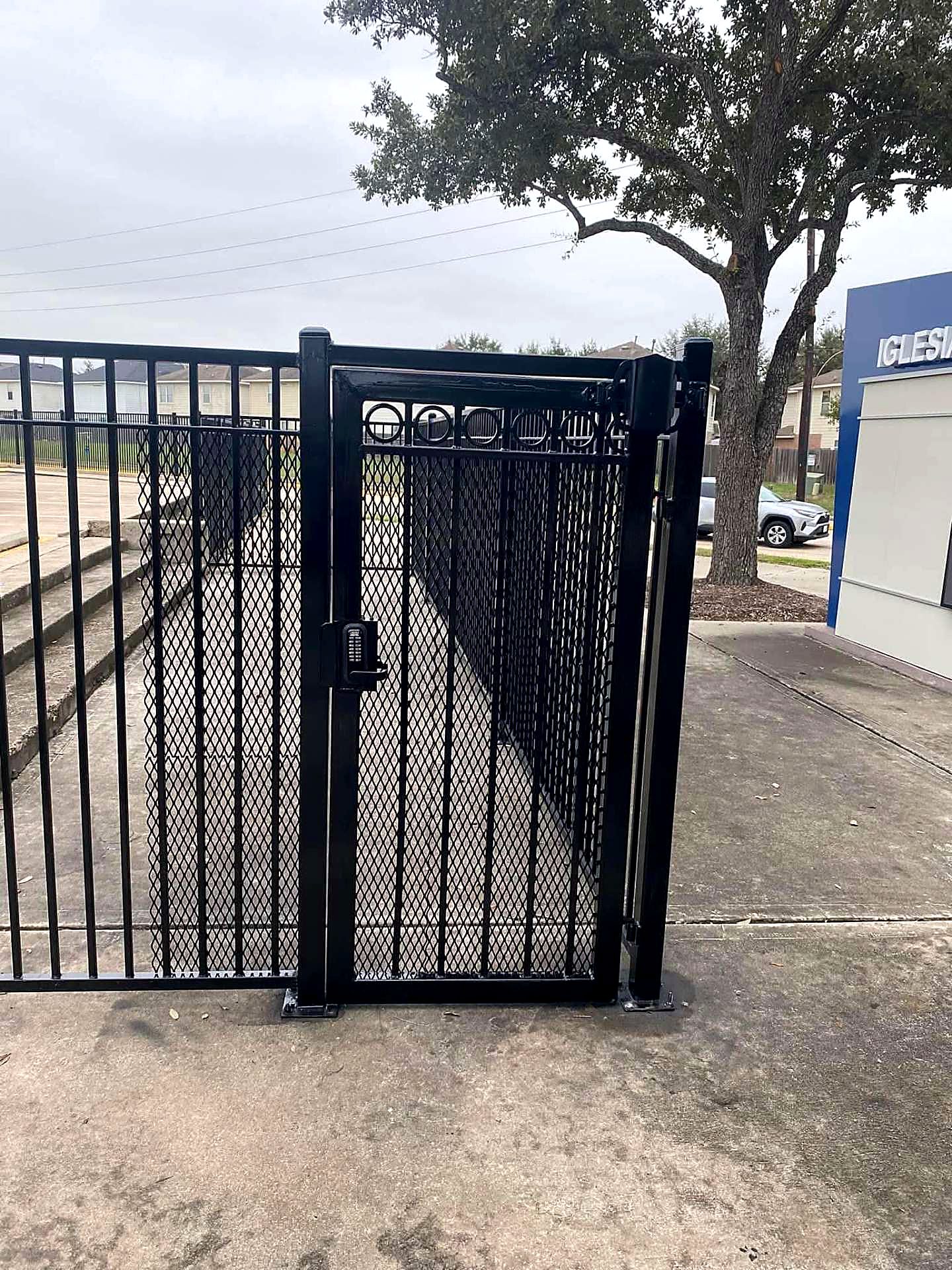 Black steel pedestrian security gate with mesh infill and keypad lock