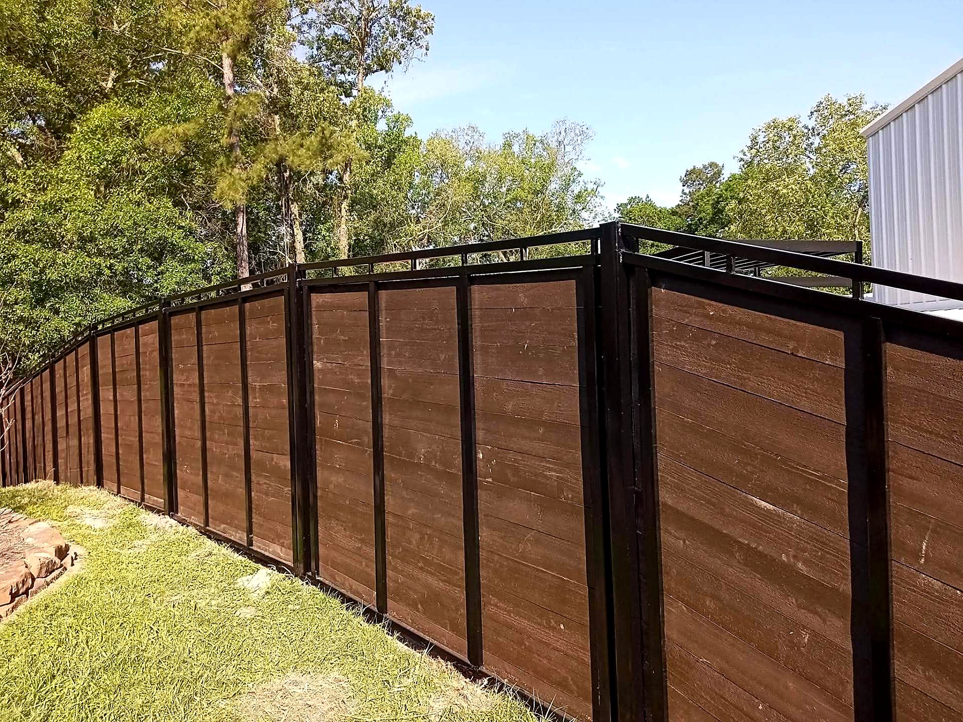 Steel-framed timber privacy fence with a decorative top rail