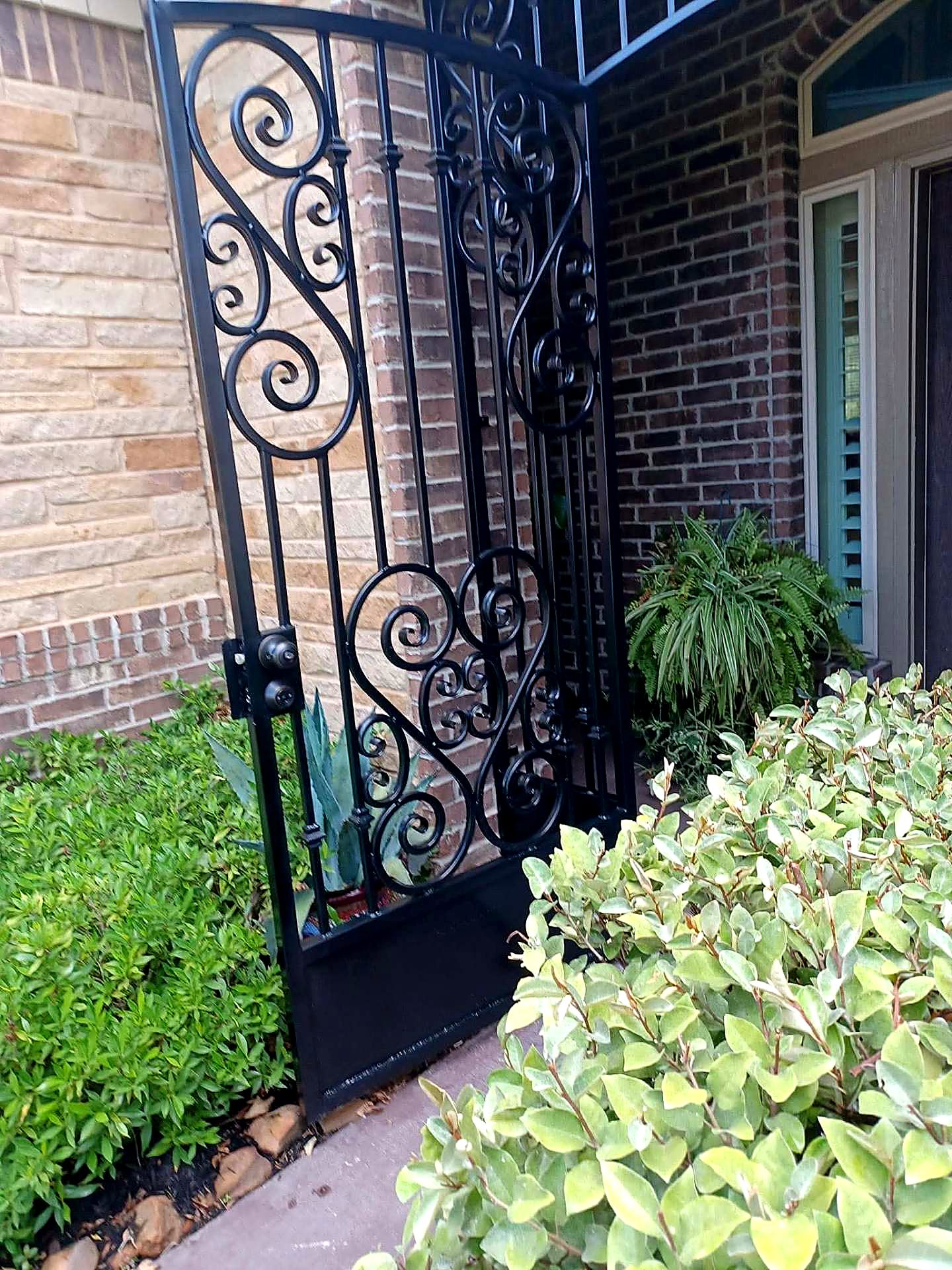 Hand-formed iron scrollwork on a side entry gate