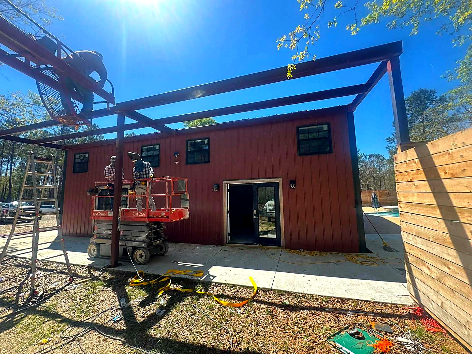 Red steel building with a welded steel patio frame going up alongside it