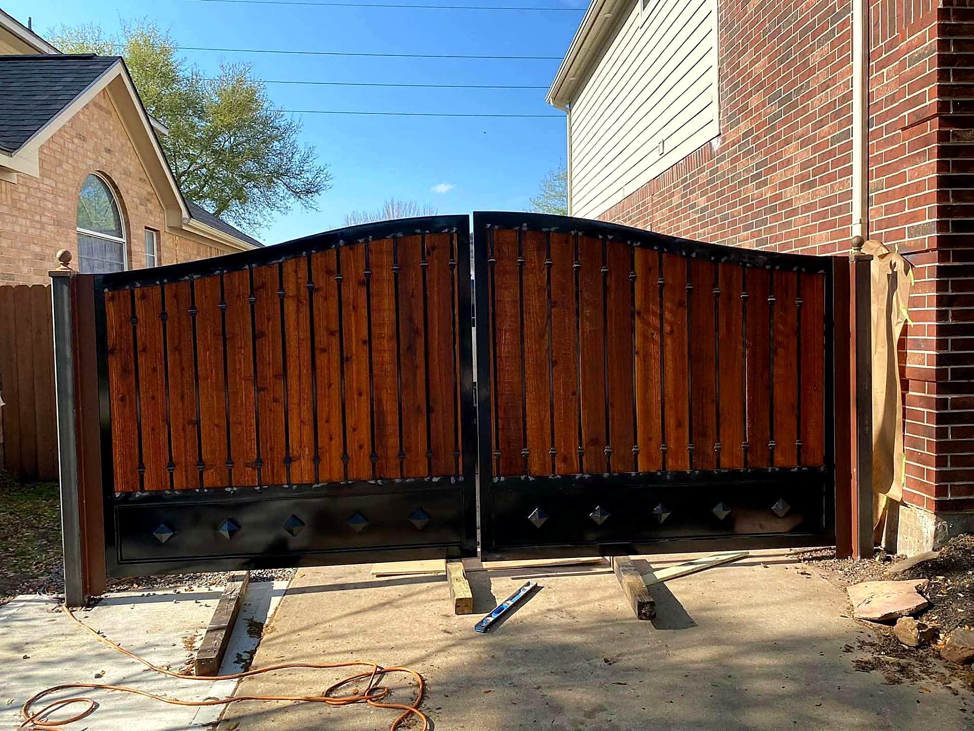 Black steel and stained cedar double driveway gate on a Houston property