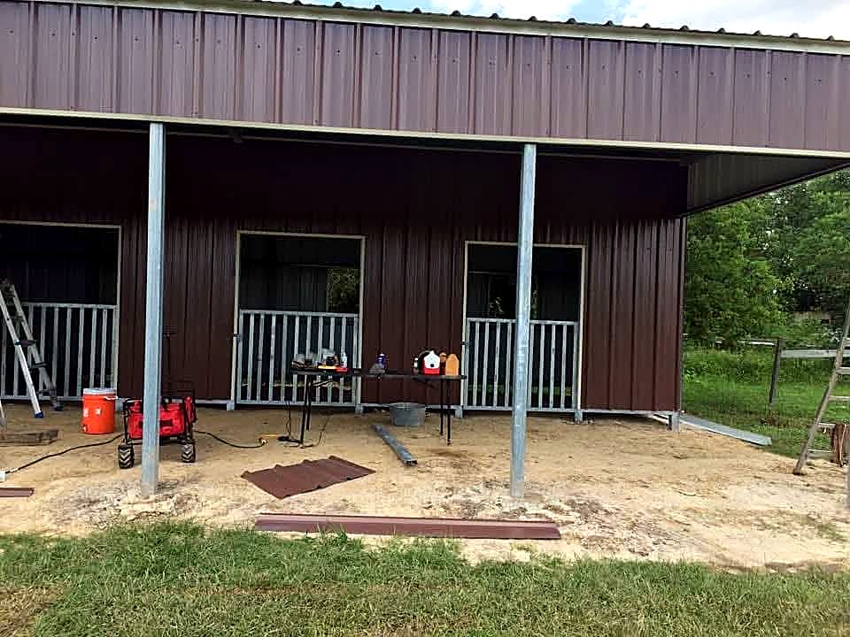 Finished brown metal barn with three stall openings and galvanised gates
