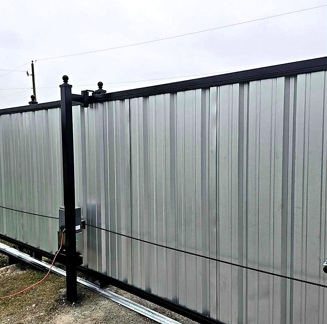 Galvanized panel sliding gate with chain drive operator on a black frame