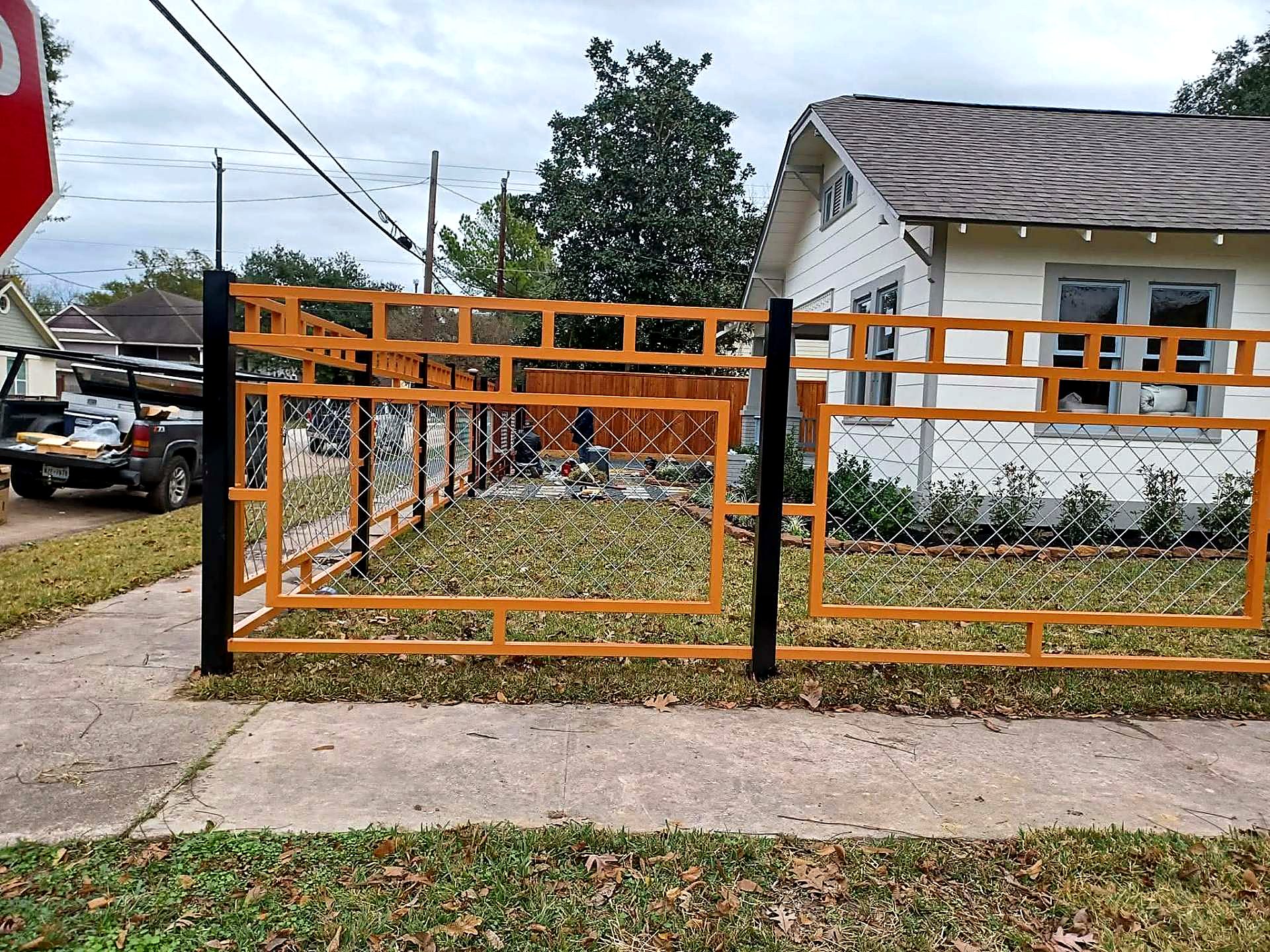 Custom orange steel fence running across a front yard in Houston