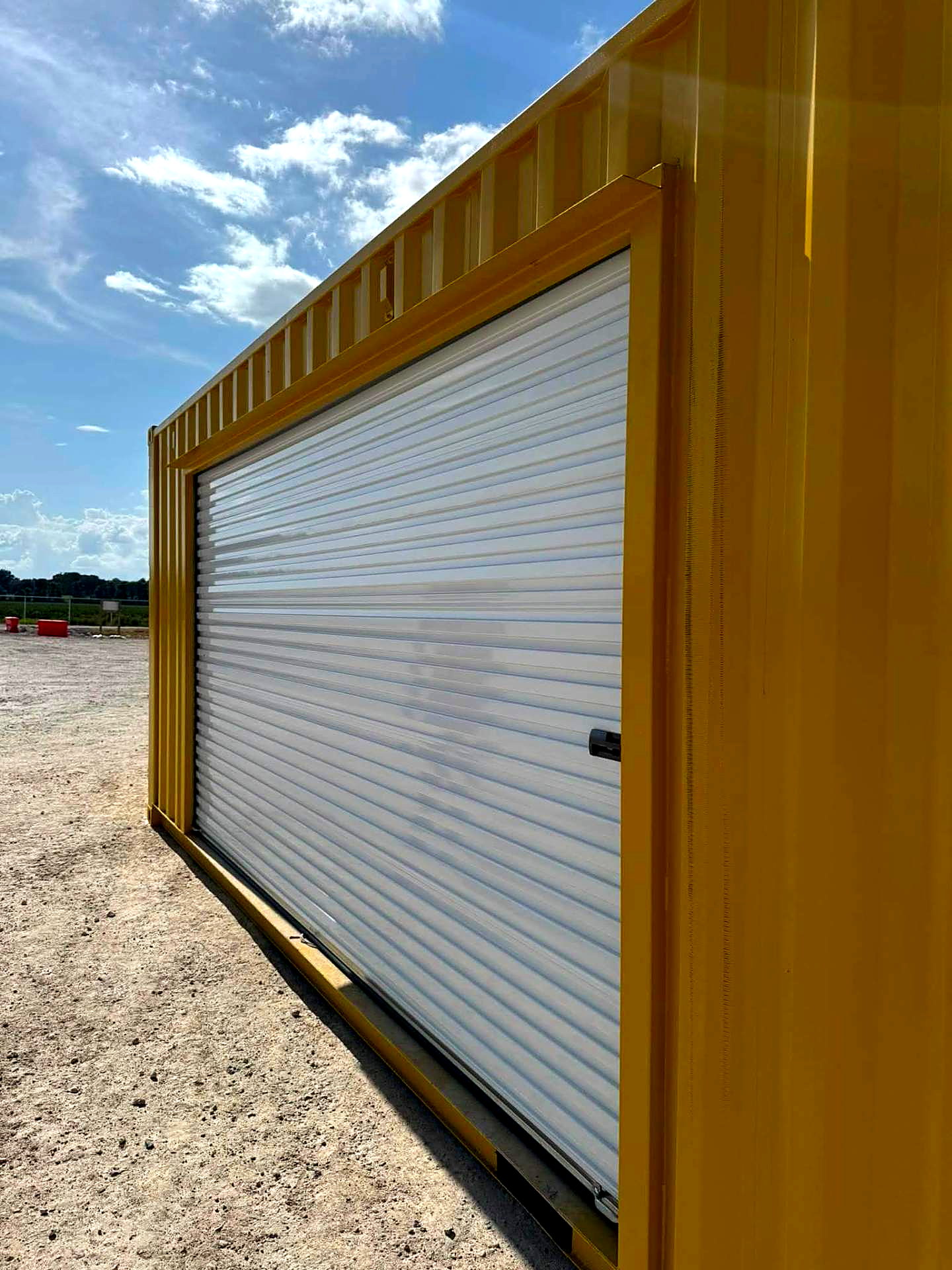 Yellow shipping container fitted with a white roll-up door