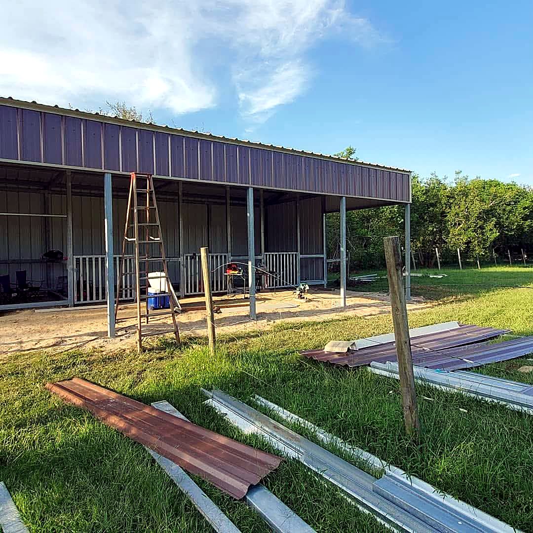 Completed brown metal shed row barn with galvanised posts and open stall bays