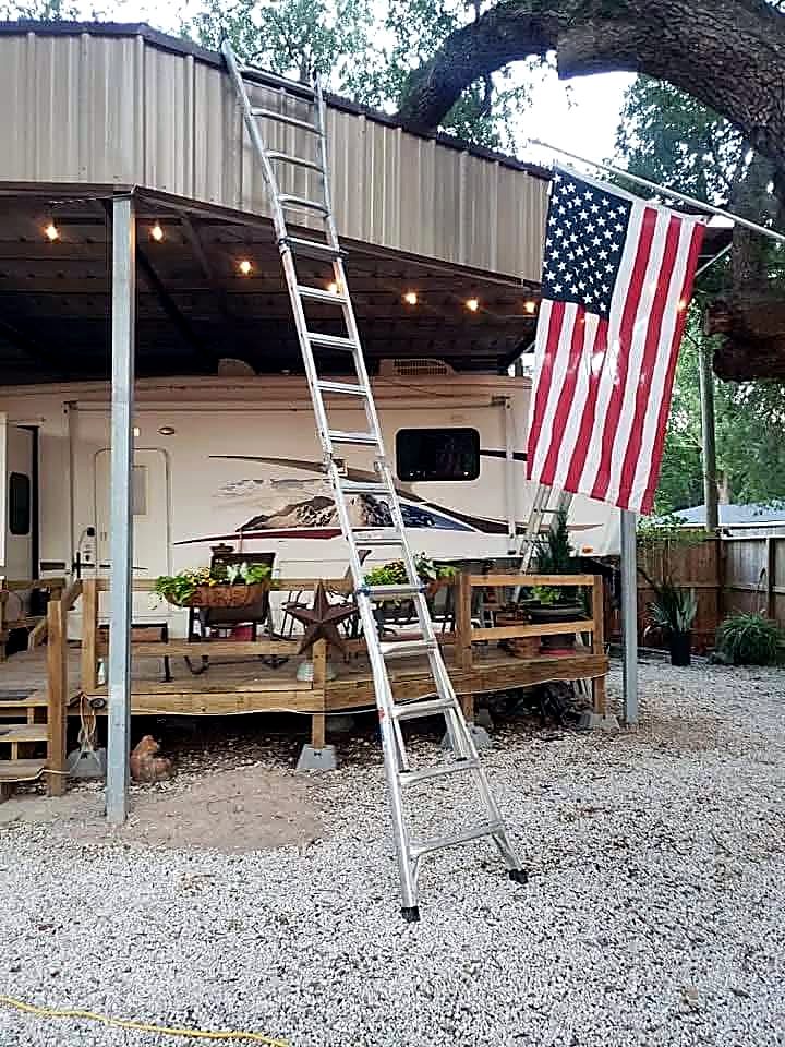 Steel RV cover over a timber deck with a flag flying from the frame