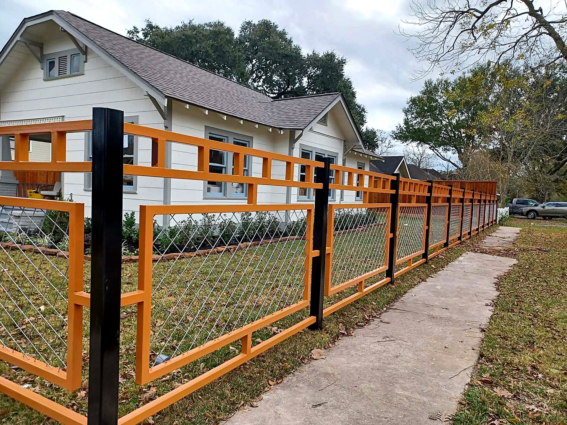 Custom orange and black steel fence panels with mesh infill at a bungalow