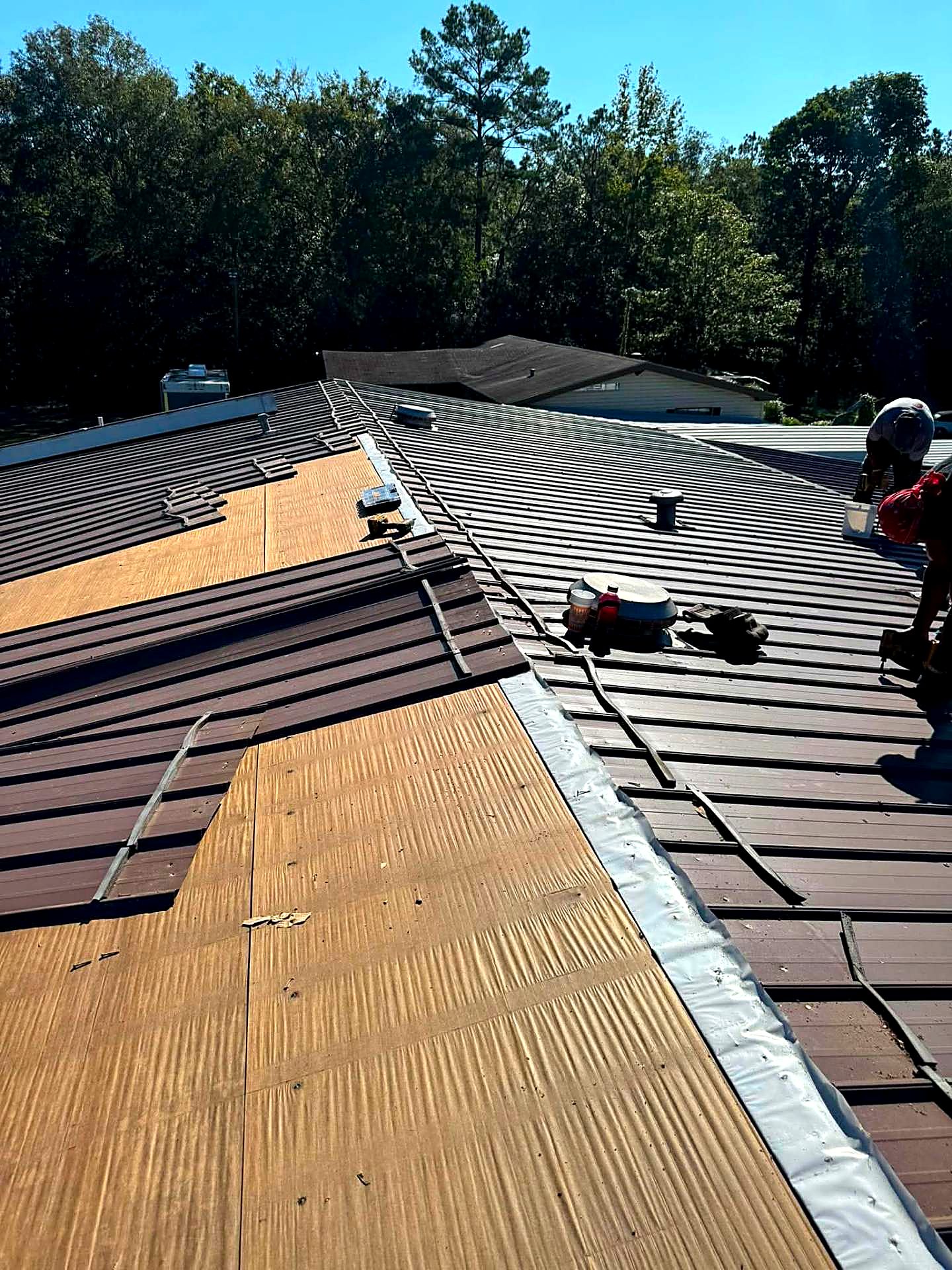 Metal re-roof in progress with panels lifted and underlayment exposed